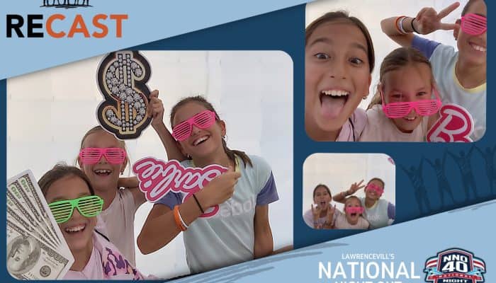 Group of kids at a photo booth with fun props and pink glasses.